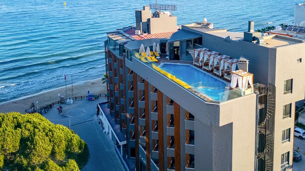 Un hôtel doté d’une piscine à débordement sur le toit, offrant une vue sur la plage, et présentant un design architectural moderne.