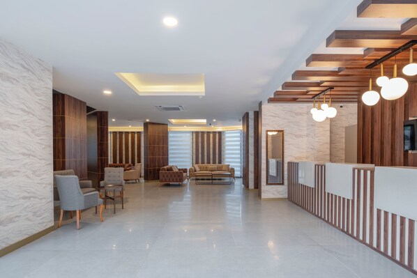 A modern lobby with a reception desk, seating area, and a staircase.