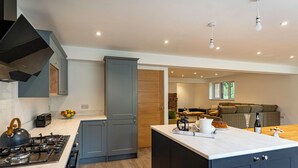 A modern kitchen with grey cabinets, a central island, and a dining area with a sofa and table.