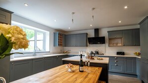 A modern kitchen with grey cabinets, a wooden dining table, and a window providing natural light.