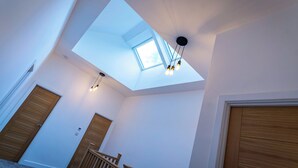A spacious room with a skylight, wooden doors, and a staircase.