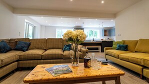 A modern living room with a brown sofa, a yellow sofa, and a wooden coffee table. There is a magazine on the table and a vase with flowers.