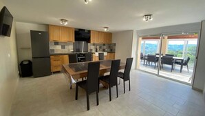 Una cocina moderna con armarios de madera, horno empotrado y comedor con mesa y sillas.