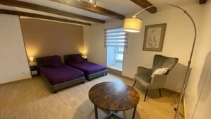 Una habitación con dos camas, una mesa redonda, una silla y una lámpara de pie.