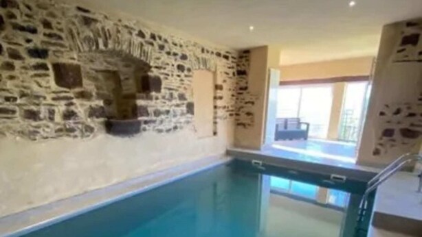 Una piscina interior con paredes de piedra y vistas despejadas al exterior.