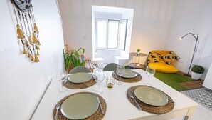 Een eethoek met een witte tafel gedekt voor vier personen, inclusief borden, bestek en glazen.