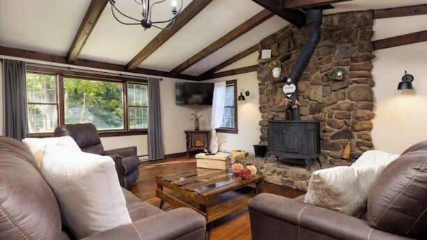 A cozy living room with leather sofas, a wooden coffee table, and a stone fireplace. - High Street Hideaway (Athol)