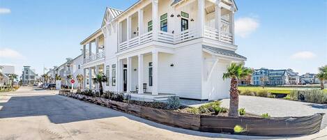 A multi-story white building with balconies, a covered porch, and a boat in the foreground.