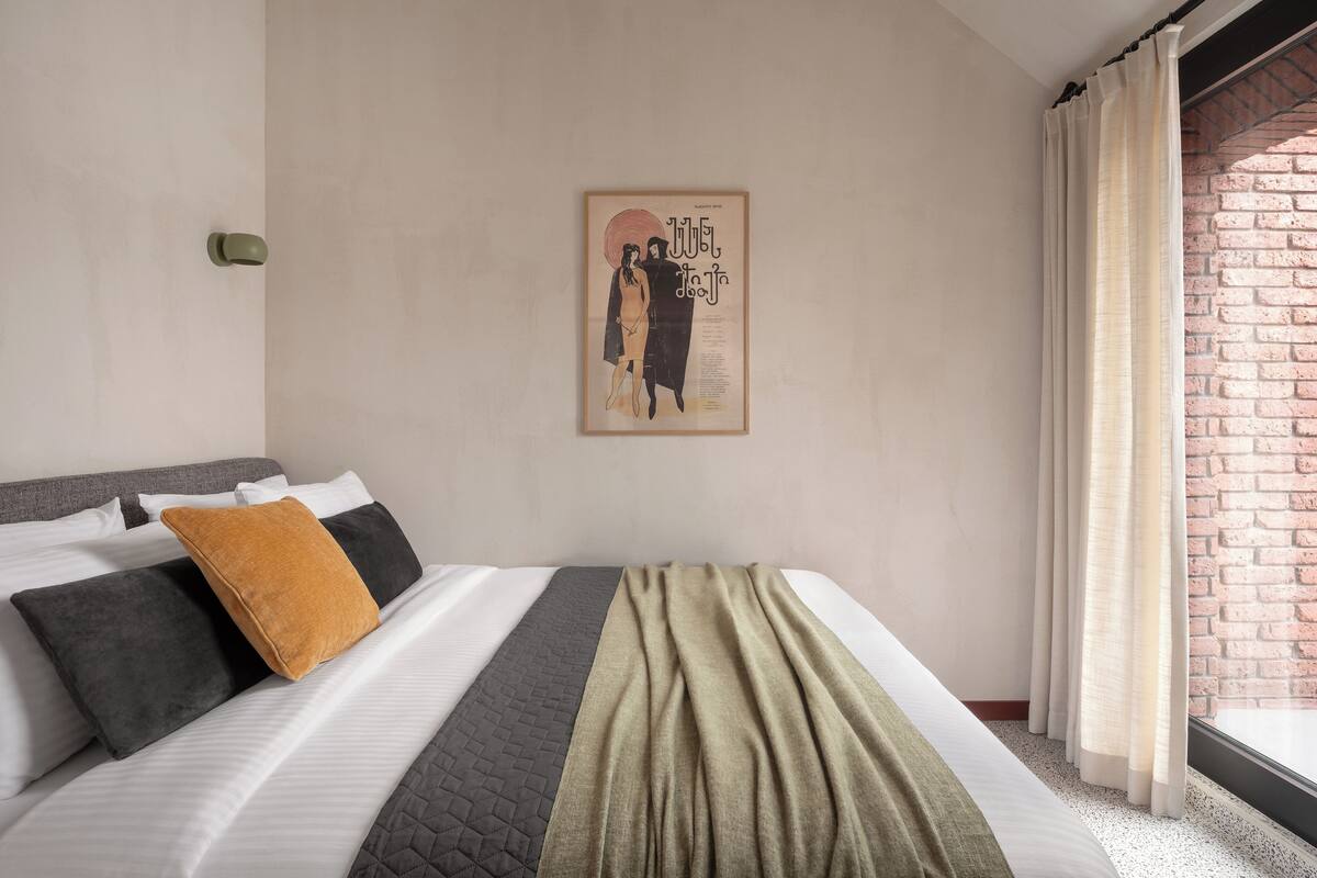 A neatly made bed with a quilt, pillows, and a blanket.