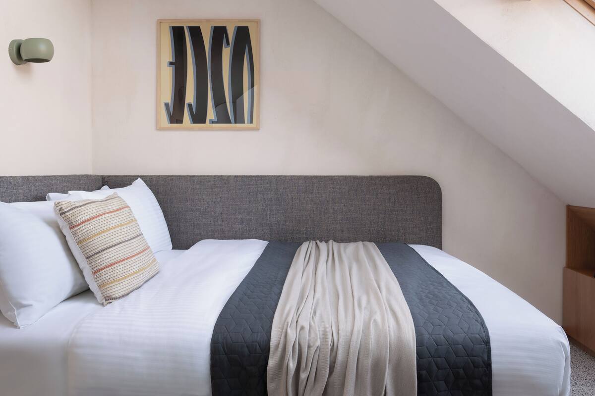 A neatly made bed with a gray headboard, a quilted blanket, and striped pillows.