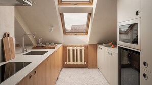 Una cocina compacta con tragaluz, electrodomésticos integrados y encimera de madera.