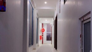 A narrow, well-lit hallway with a tiled floor leading to a door at the end. - Hotel Majesty inn (Jaipur)