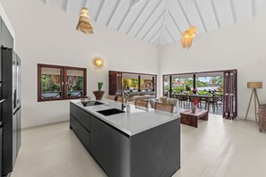 A spacious kitchen with a large island, modern appliances, and a view of the outdoor patio area.