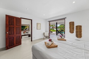 A hotel room with a large bed, a wooden door, a view of the outdoor pool, and a balcony.
