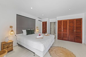 A modern bedroom with a large bed, wooden wardrobe, and a bedside table with a lamp.