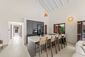 Una cocina moderna con una isla central, taburetes de bar y una mesa de comedor.