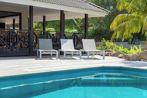A poolside area with lounge chairs and a covered seating area.