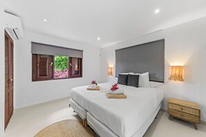 Quarto moderno com uma cama grande, abajures, uma janela com persianas e uma pequena mesa de cabeceira.