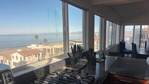 A kitchen with a large window overlooking a beach and cityscape. - Gorgeous beachfront house with stunning views, light and the sounds of the ocean (Manhattan Beach)