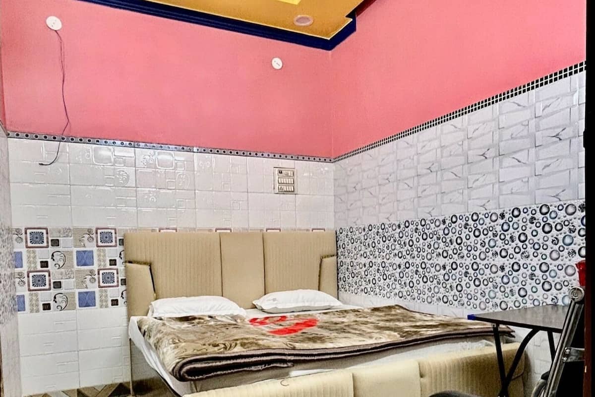 A bedroom with a bed, a chair, a ceiling fan, patterned tiles, and a tiled wall.