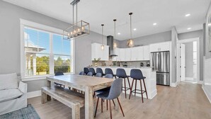Una cocina moderna con una isla central, taburetes de bar y una mesa de comedor.