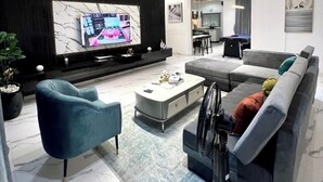A modern living room with a large TV, a sofa, a coffee table, and a TV stand. - Affable Apartments (Lagos)