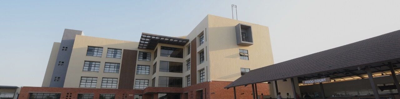 Un edificio de varios pisos con techo plano y un área cubierta donde se lee "FOOD COURT" al frente.