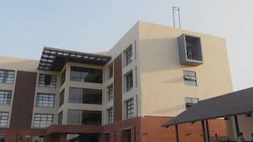 Un edificio de varios pisos con techo plano y un área cubierta donde se lee "FOOD COURT" al frente.