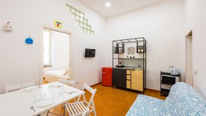 A compact living space with a kitchenette, a dining area, and a bed.