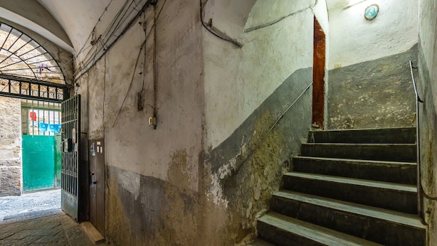 A staircase with a green door at the top, a stone wall, and a metal railing.