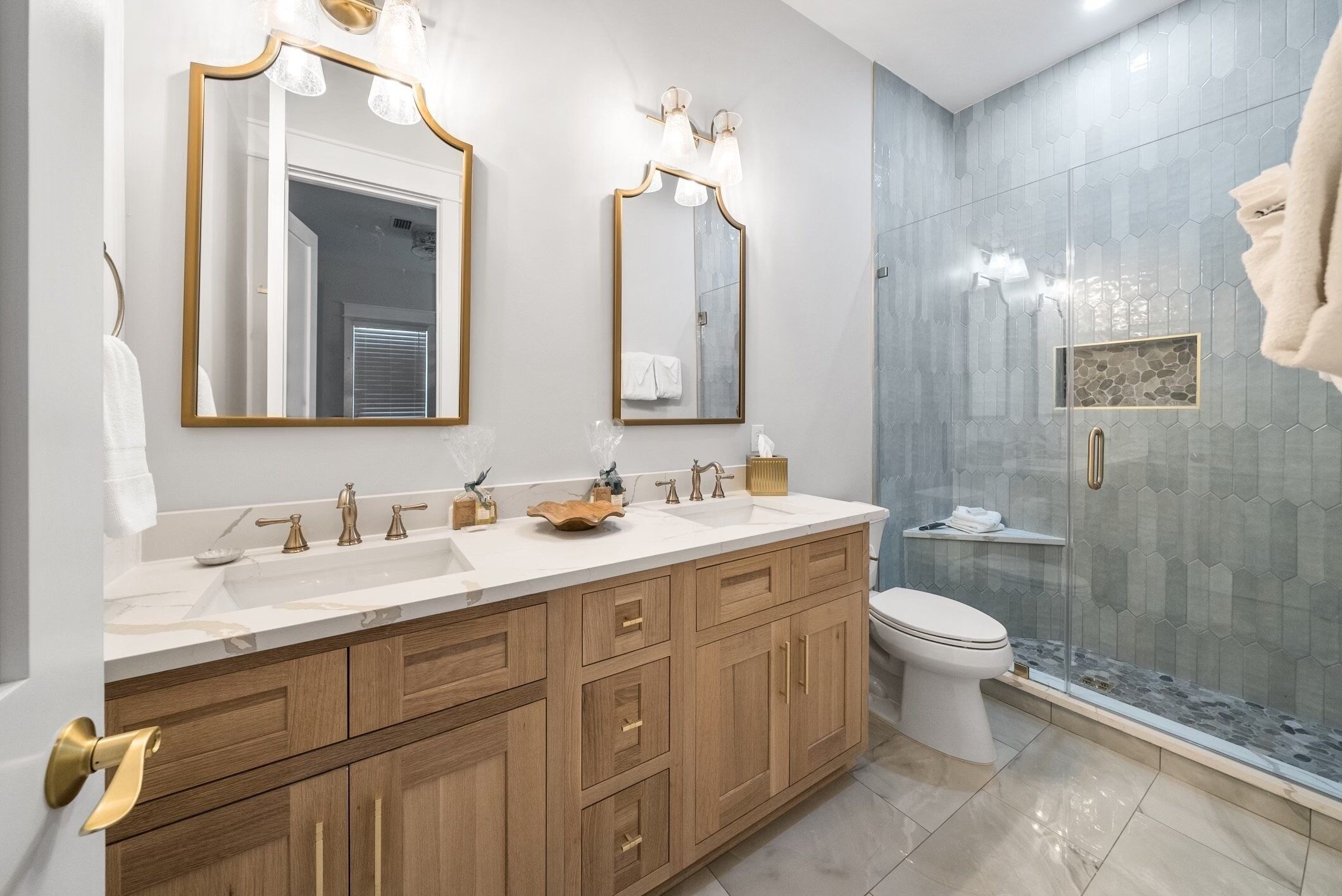Une salle de bain moderne avec un meuble-lavabo à deux vasques, des toilettes et une douche à paroi de verre.