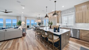 A spacious kitchen with a central island, wooden cabinets, and a view to the ocean. - Blessing At Pier Park 6 Bedroom Home (Panama City Beach)