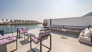 A rooftop terrace with a pool, seating areas, and a view of a rocky coastline. - Sumptuous 5BR with Assist Rm in Al Dana Island, Sharm, Fujairah by Deluxe Holiday Homes (Fujairah)