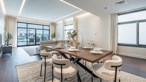 A modern dining area with a long table, chairs, and a vase of flowers. - Sumptuous 5BR with Assist Rm in Al Dana Island, Sharm, Fujairah by Deluxe Holiday Homes (Fujairah)
