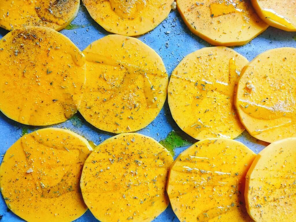 A close-up of sliced yellow fruits, possibly mangoes, seasoned with herbs.