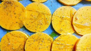 A close-up of sliced yellow fruits, possibly mangoes, seasoned with herbs.