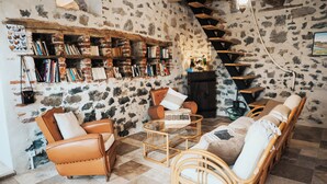 A cozy room with a stone wall, a bookshelf filled with books, a fireplace, and comfortable seating. - Ch. d'hôtes La clef des champs - THE SOURCE OF OUR ROOTS - FERMETTE - AVESNOIS (Beaufort)