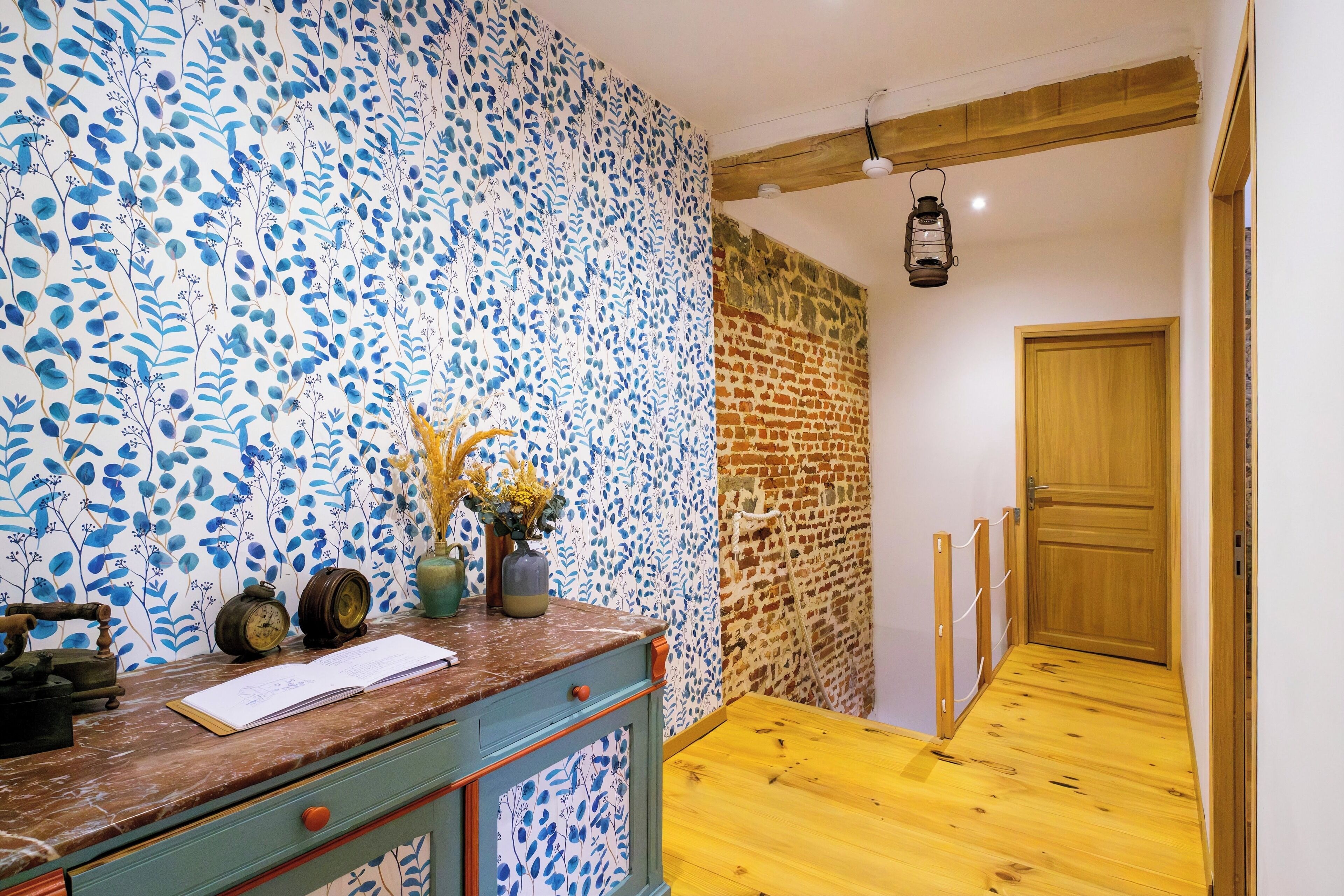 A hallway with a wooden floor, a brick wall, and a wooden door.