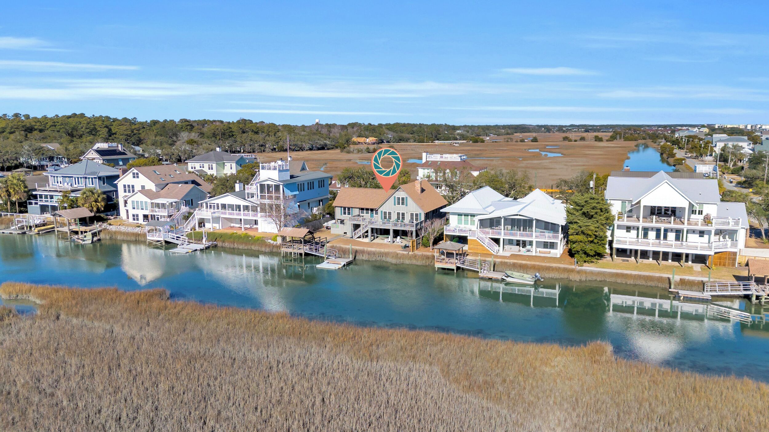 A coastal residential area with houses along a waterway, docks, and a clear sky.