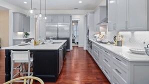 A modern kitchen with a central island, stainless steel appliances, and pendant lighting.