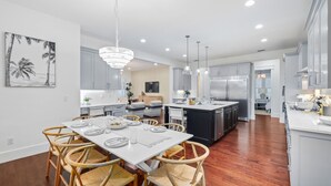 A modern kitchen with white cabinetry, a central island, and a dining area with wicker chairs.