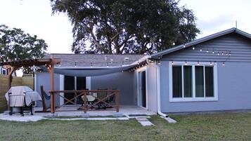 A house with a covered patio, a barbecue setup, and a string of lights.