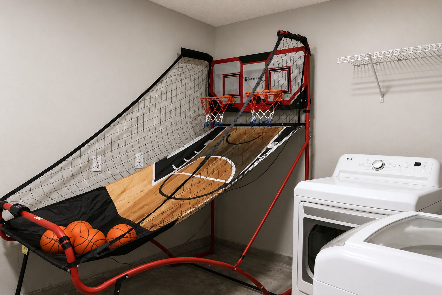 Ein Basketballkorb mit Netz, ein Holzboden und eine Waschmaschine.
