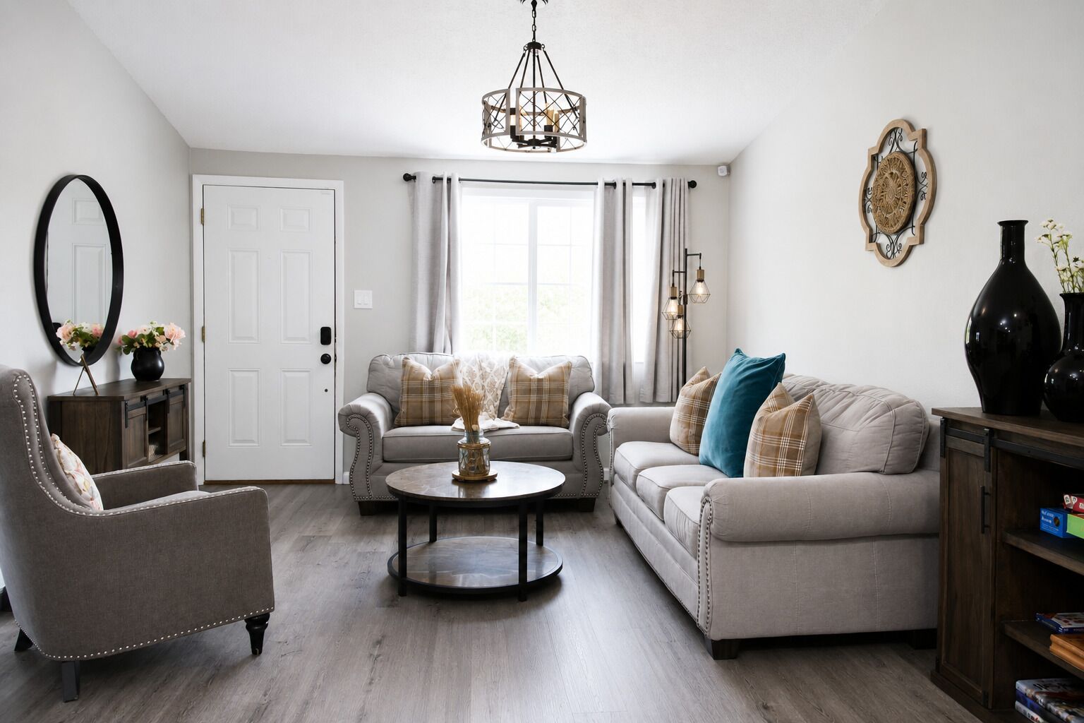 A living room with a sofa, armchair, and coffee table, a chandelier, and a door with curtains.