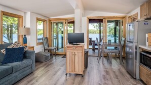 A spacious living area with a sofa, TV, wooden cabinet, and a dining table with chairs.