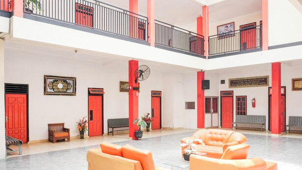 Un hall d’entrée spacieux, à deux niveaux, avec des portes rouges et des coins salon aux couleurs orange.