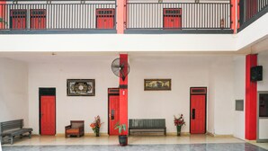 Un vaste atrium doté de portes rouges, d’un ventilateur, de bancs et de plantes en pot.