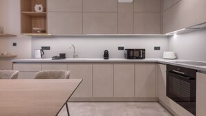 A modern kitchen with a central island, built-in appliances, and a dining area with a table and chairs. - Phaedrus Living Athens Residences Golden (Athens)