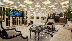 A hotel lobby with a reception desk, seating area, and a large screen. - Bogishamol Hotel (Samarkand)