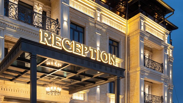 A grand hotel reception with a large illuminated sign, a covered entrance, and a water feature in front. - Bogishamol Hotel (Samarkand)